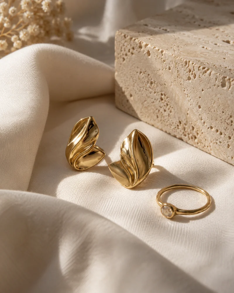 Pendientes y un anillo dorados sobre una tela de lino.
