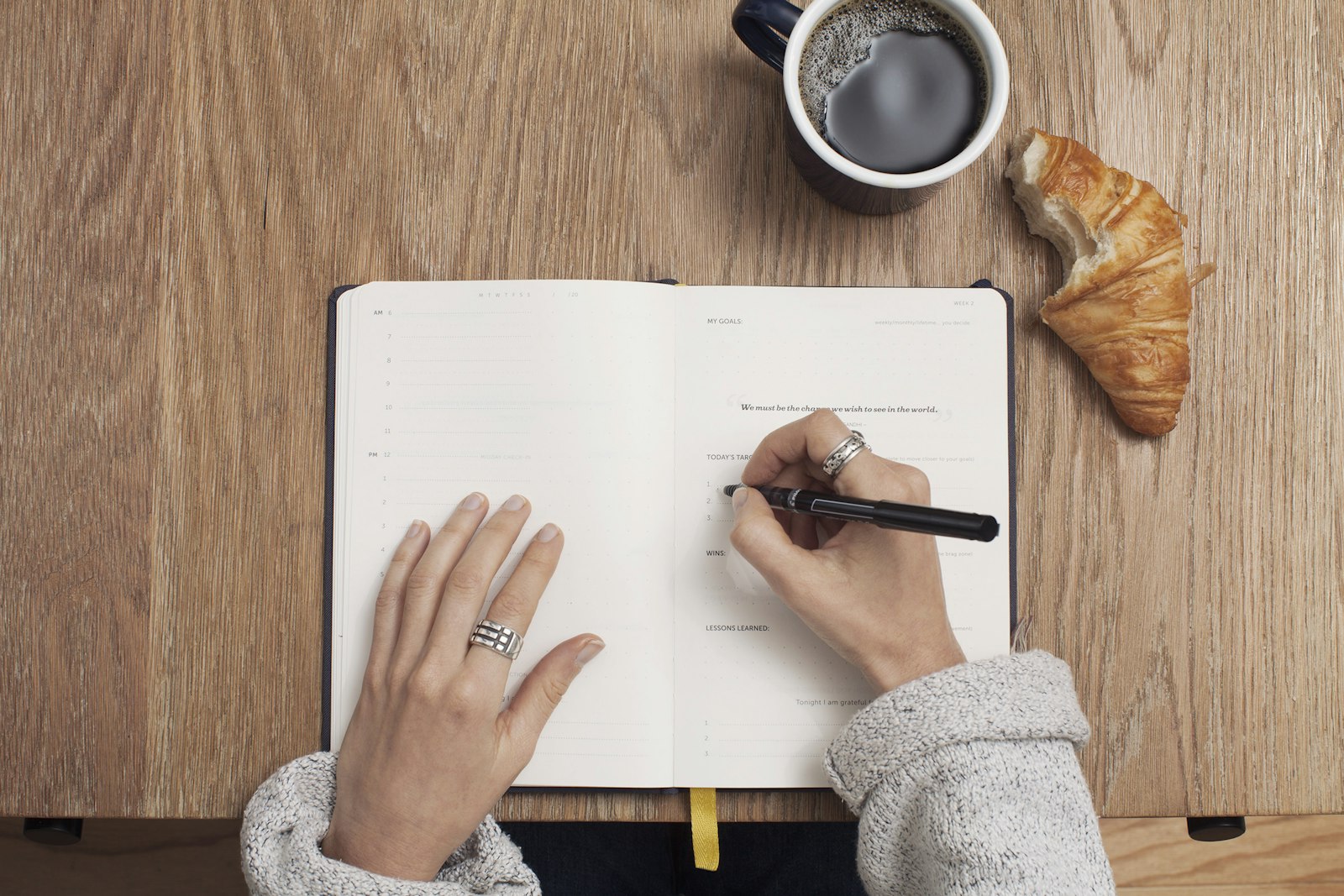 Manos de una clienta escribiendo en su agenda junto a un café — del blog y de las reseñas nos ocupamos nosotros